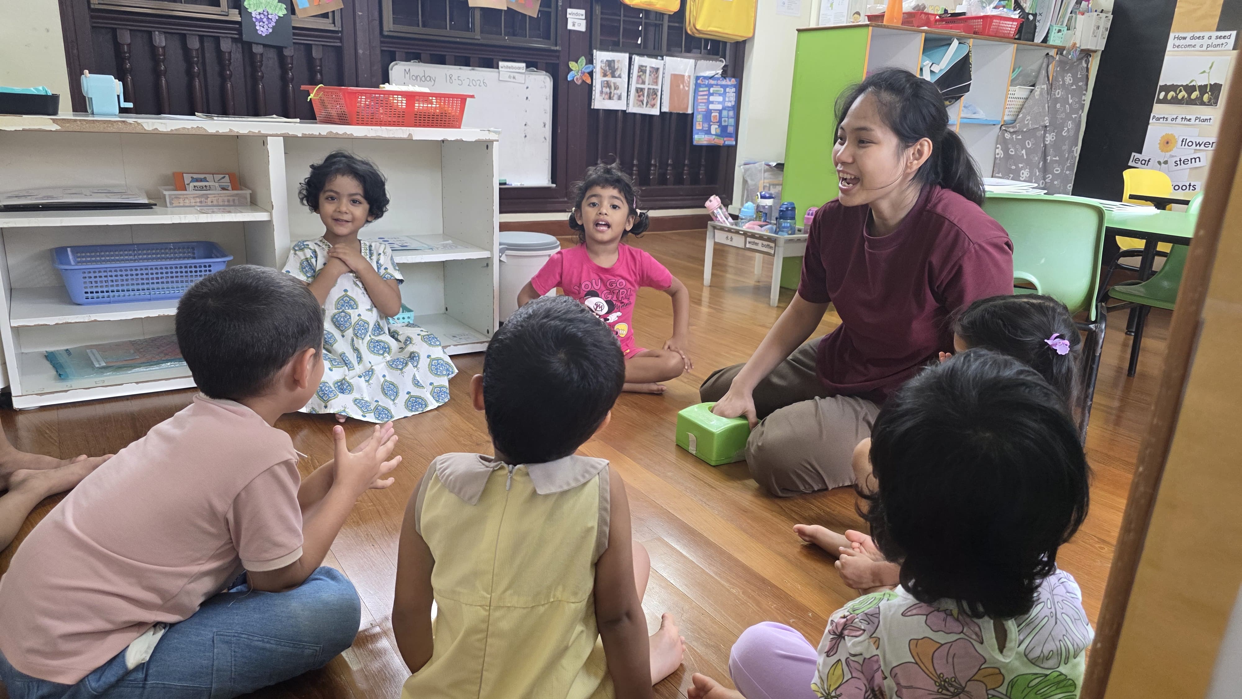 Teacher sitting in a circle with five children during a group learning activity at Genius Gems Childcare Centre
